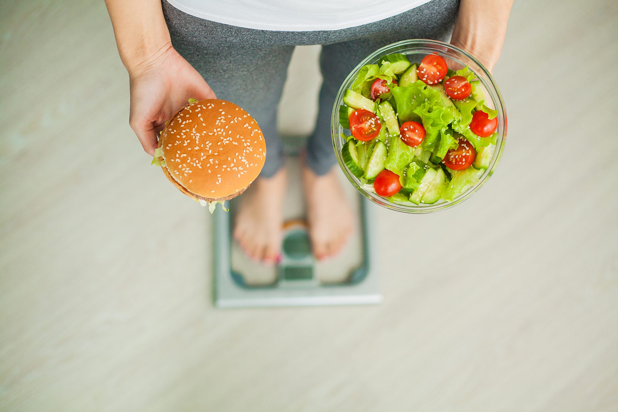 Dieting concept, beautiful young woman choosing between healthy food and junk food.